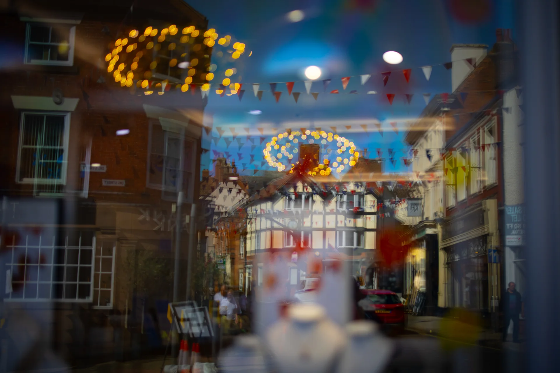 Ashbourne town centre reflected in a shop window with bunting and warm lights