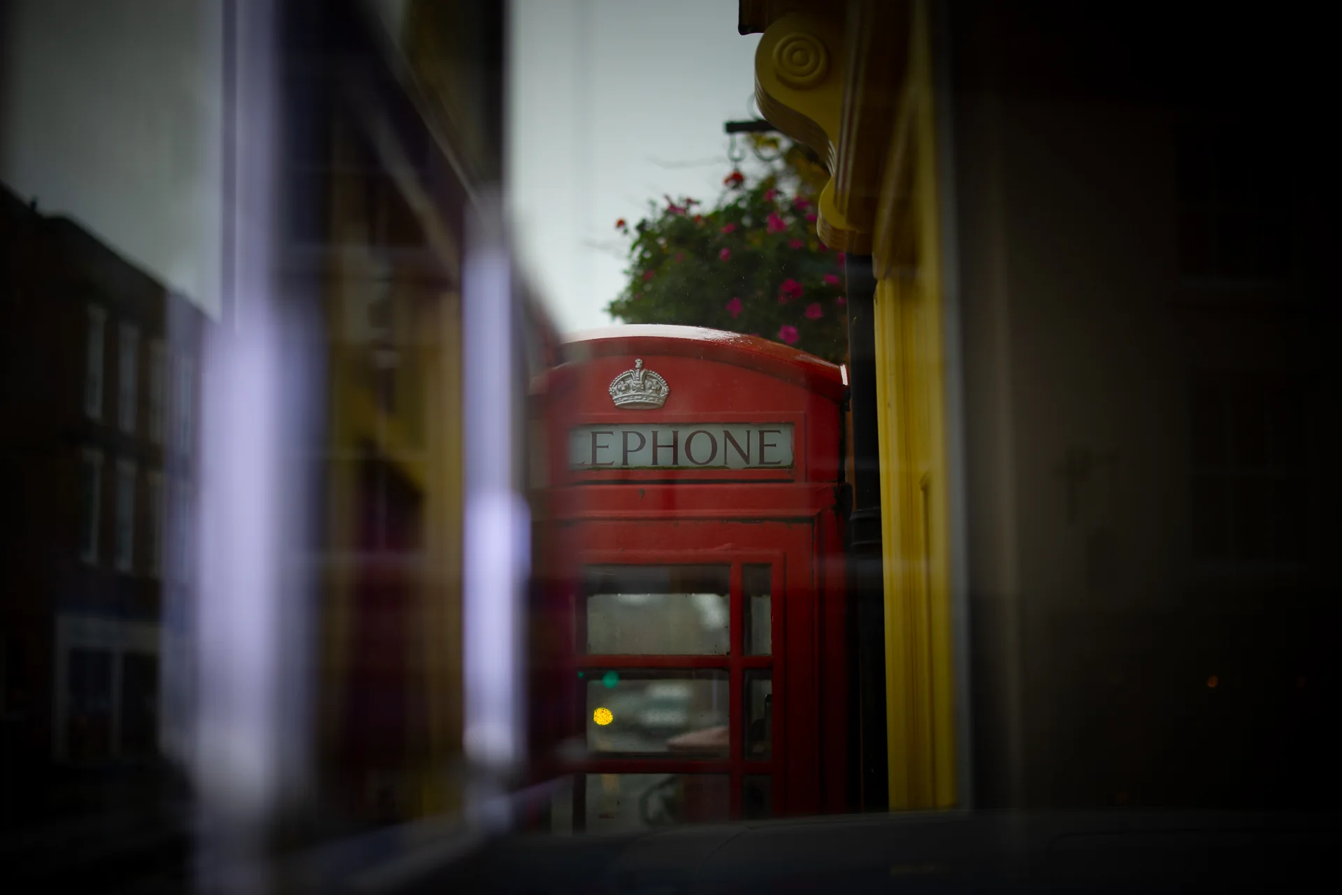 Red telephone box reflected beside an Ashbourne shopfront
