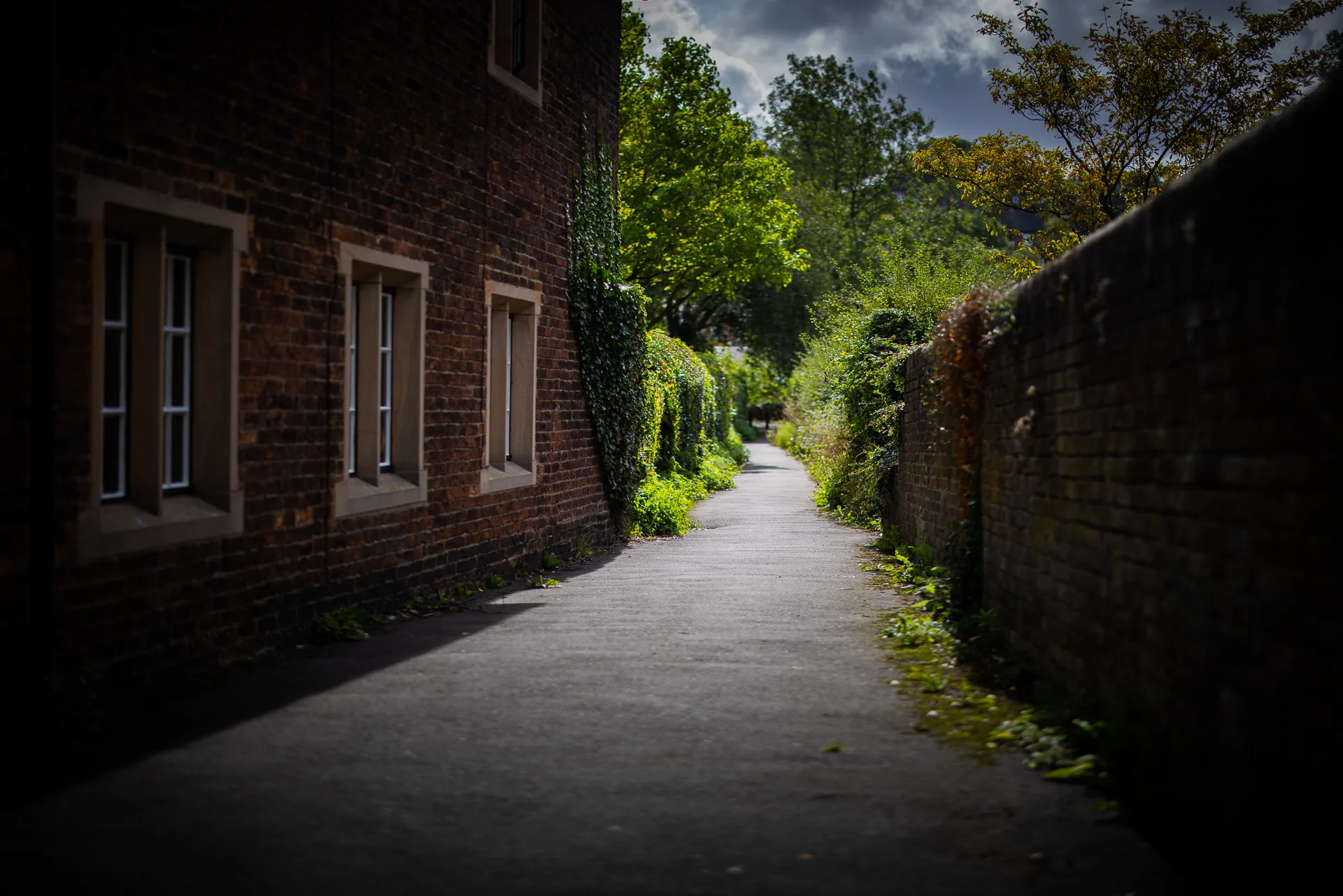 Quiet path between brick buildings and a stone wall